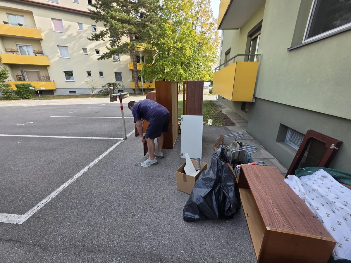 Individuelle Planung – Abtransport zerlegter Möbel Individuelle Planung beim Abtransport – Mitarbeiter bereitet zerlegte Schränke und Möbelteile vor einem Wohnhaus zum Transport vor